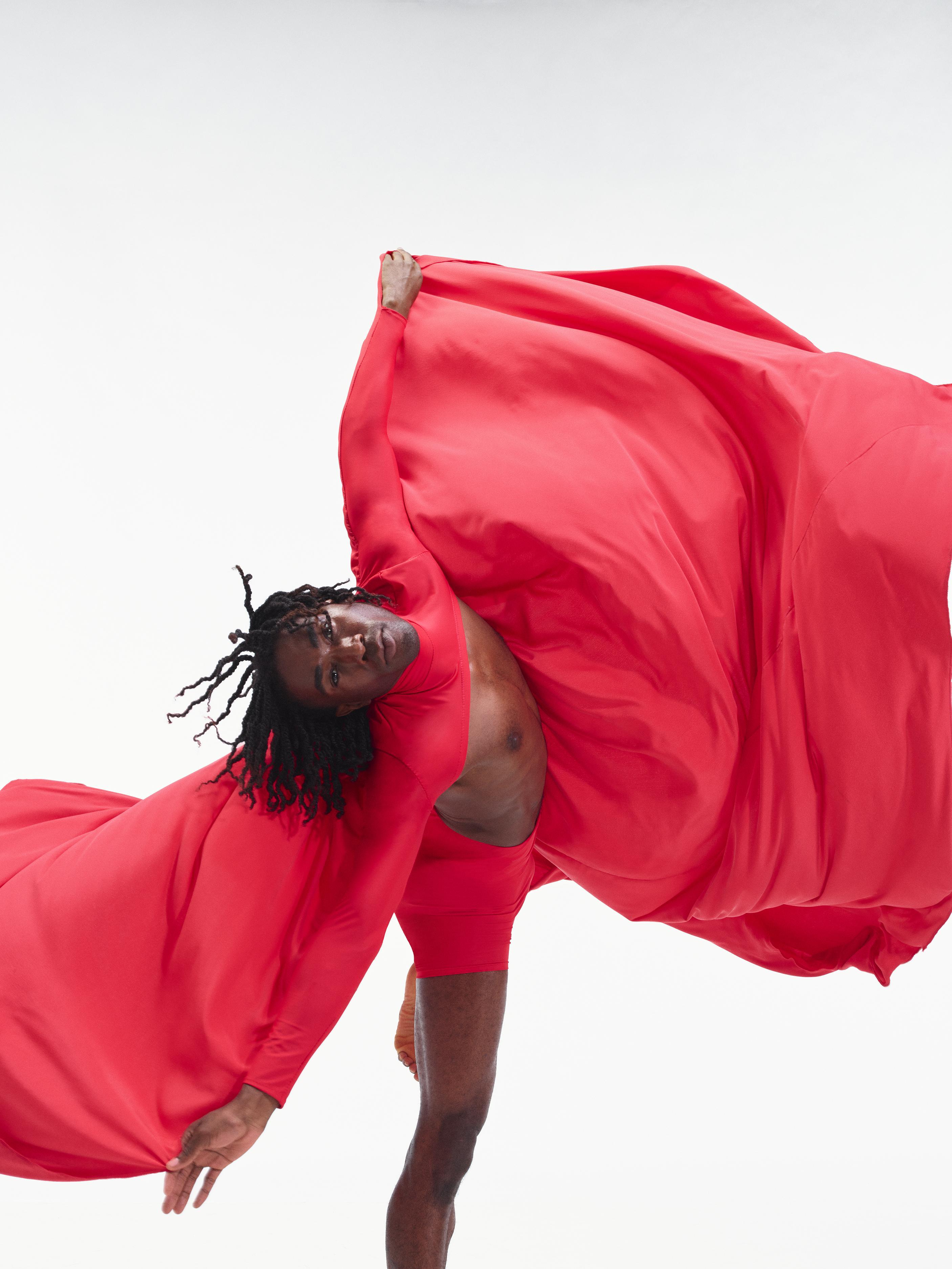 a dancer spins around with red fabric billowing around him