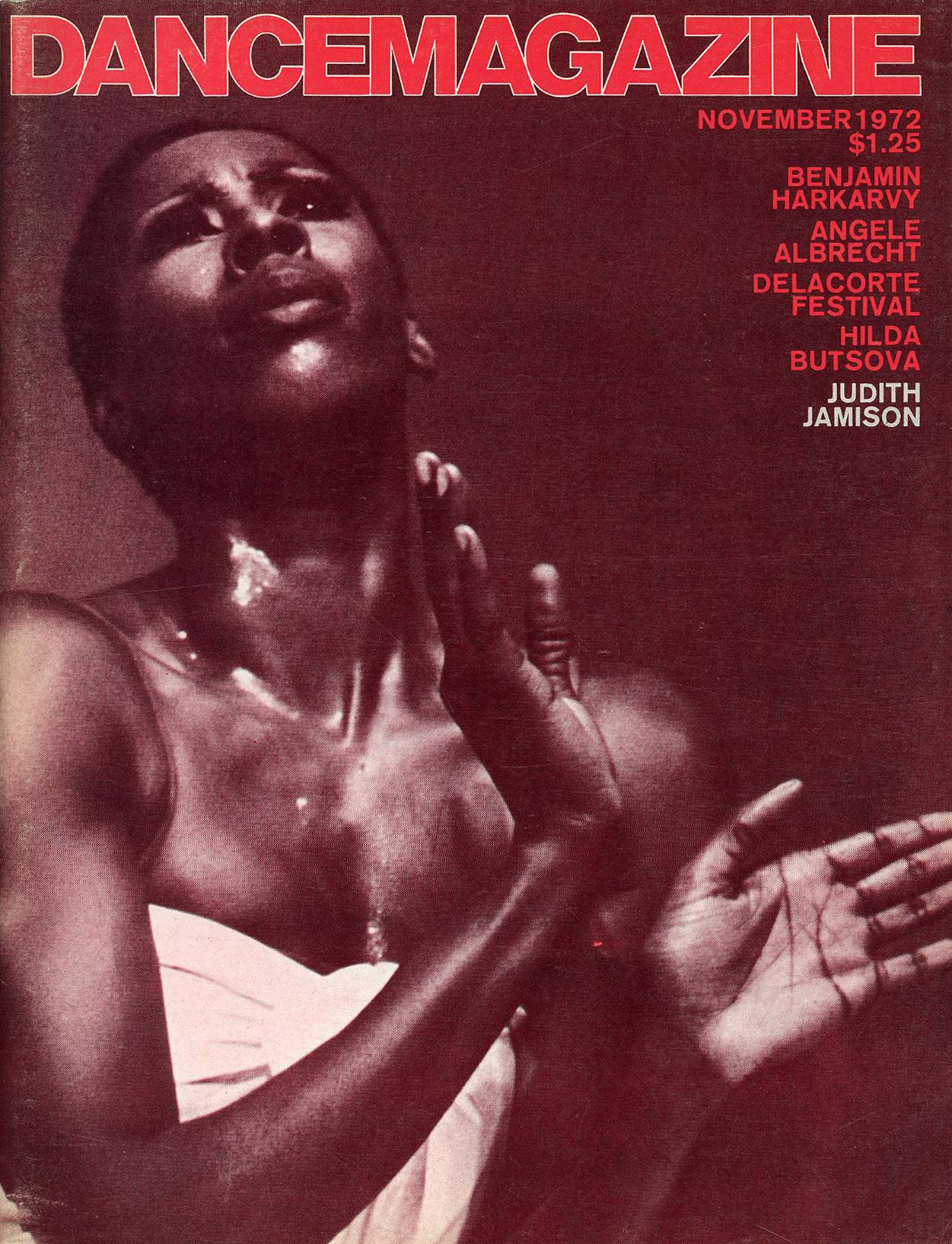 A cover of Dance Magazine. There is a black dancer posed in a white top. The entire magazine has a red filter on top.