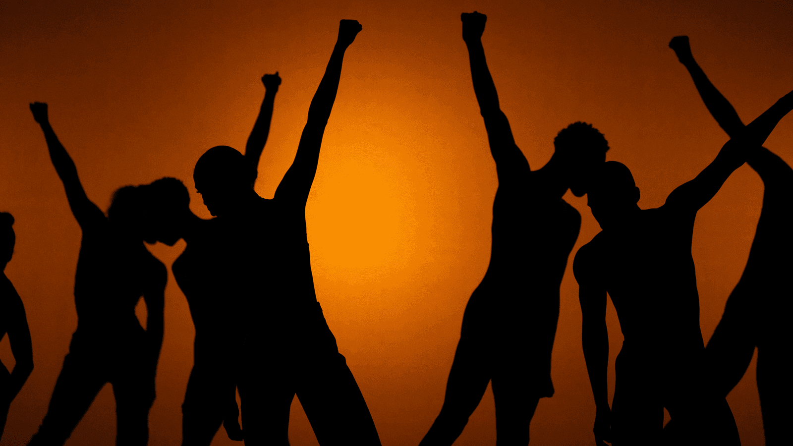 Silhouettes of dancers with raised fists against an orange background.