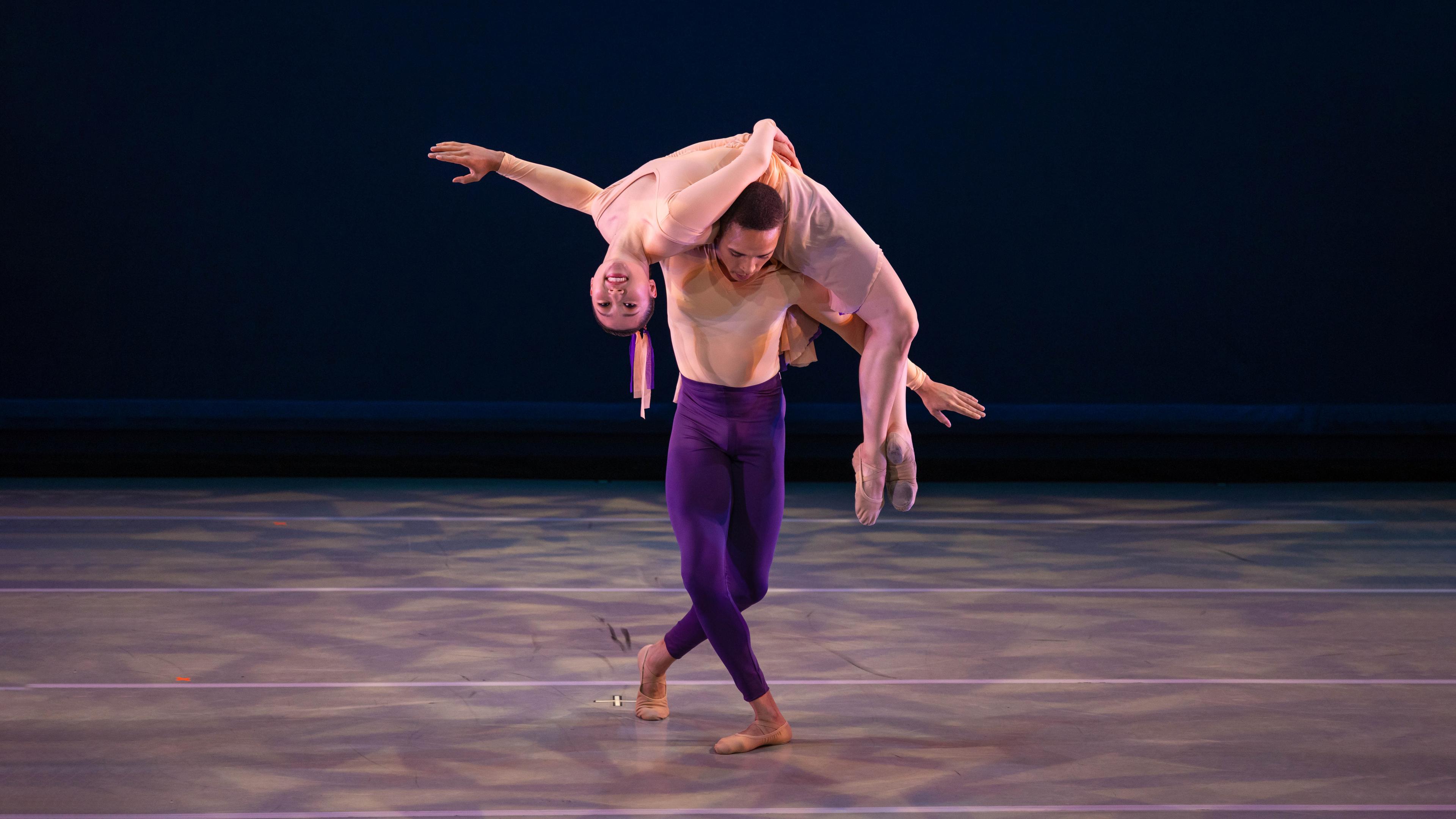 A man holds a woman laying across his upper back