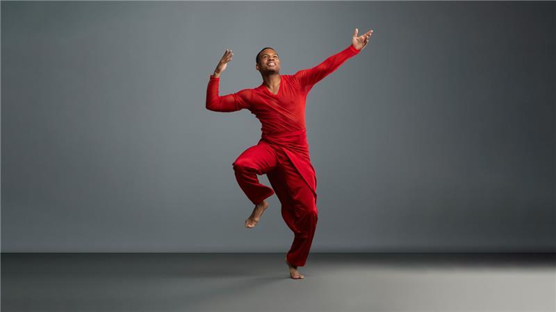 Dancer in red. He is dancing in a grey studio.