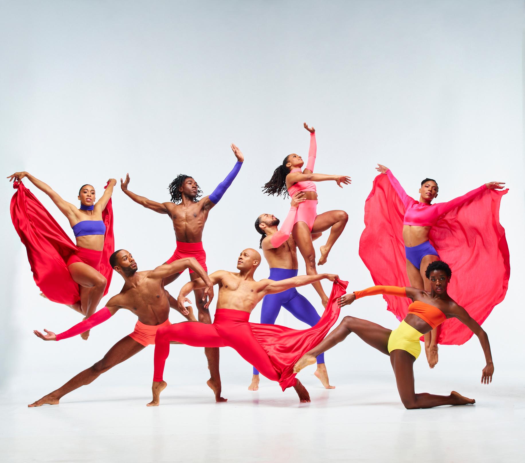 A group of dancers wearing brightly colored clothing pose together