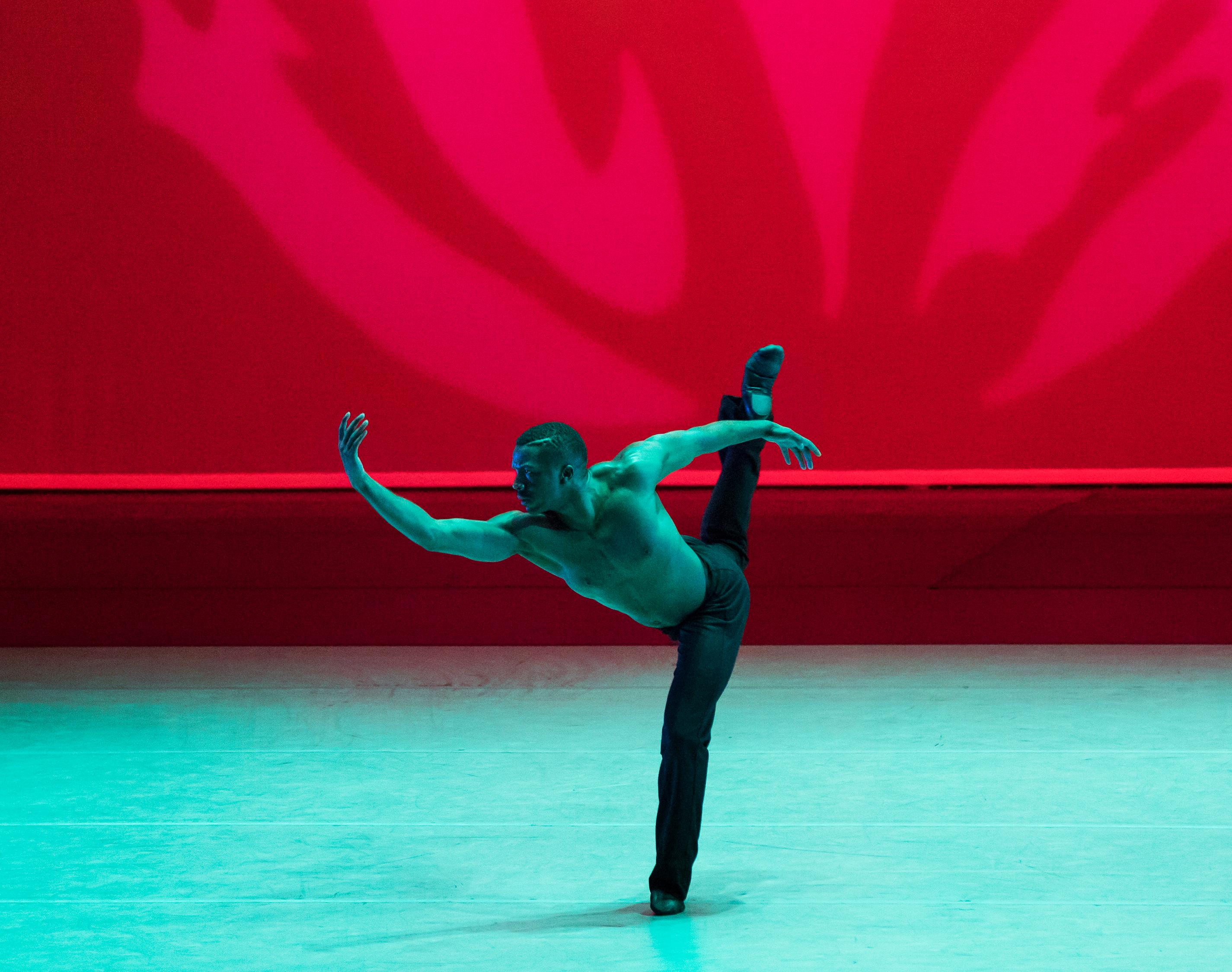 One dancer with black pants, one leg backward in attitude and one arm curved forward