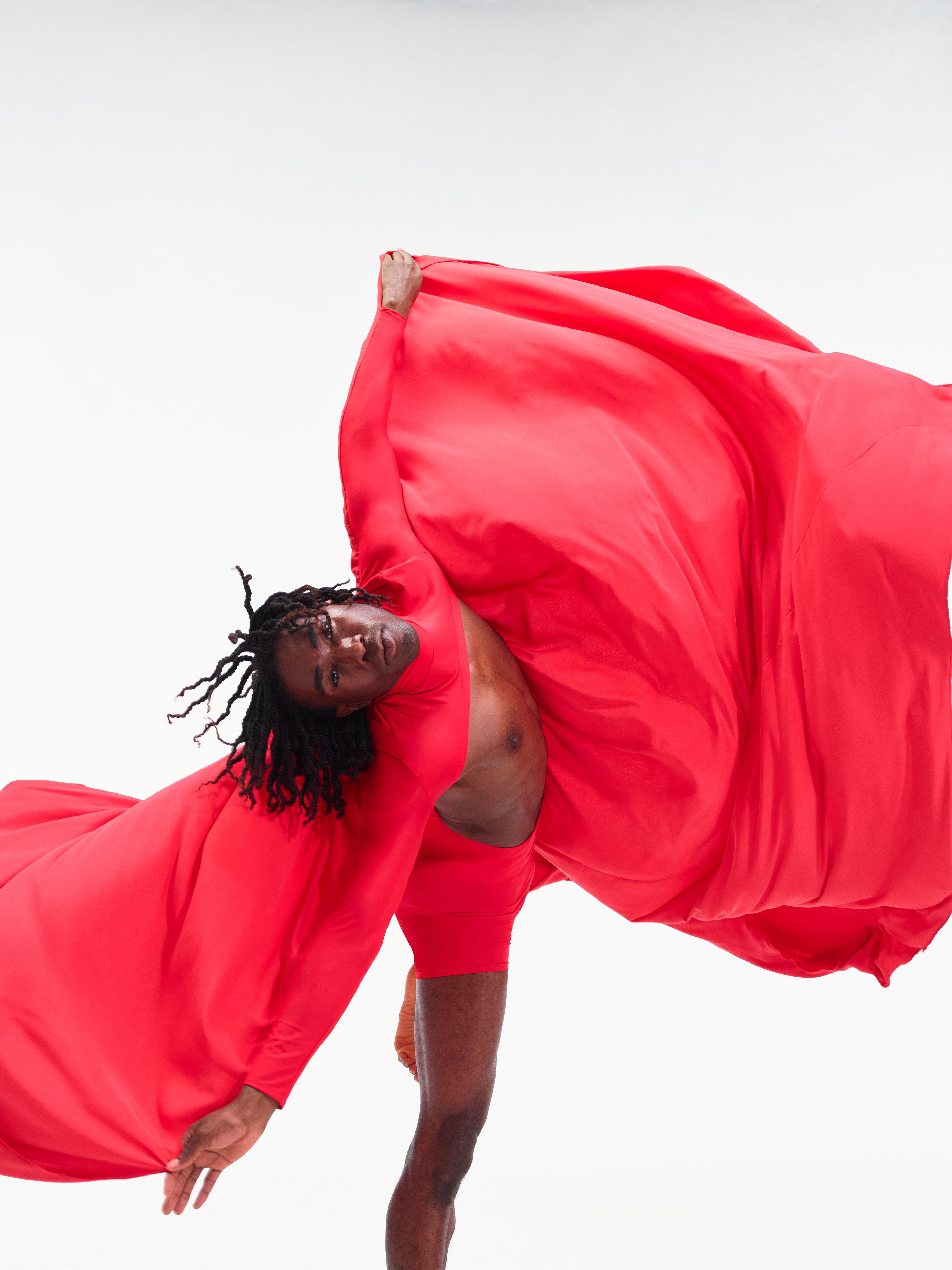 a dancer spins around with red fabric billowing around him