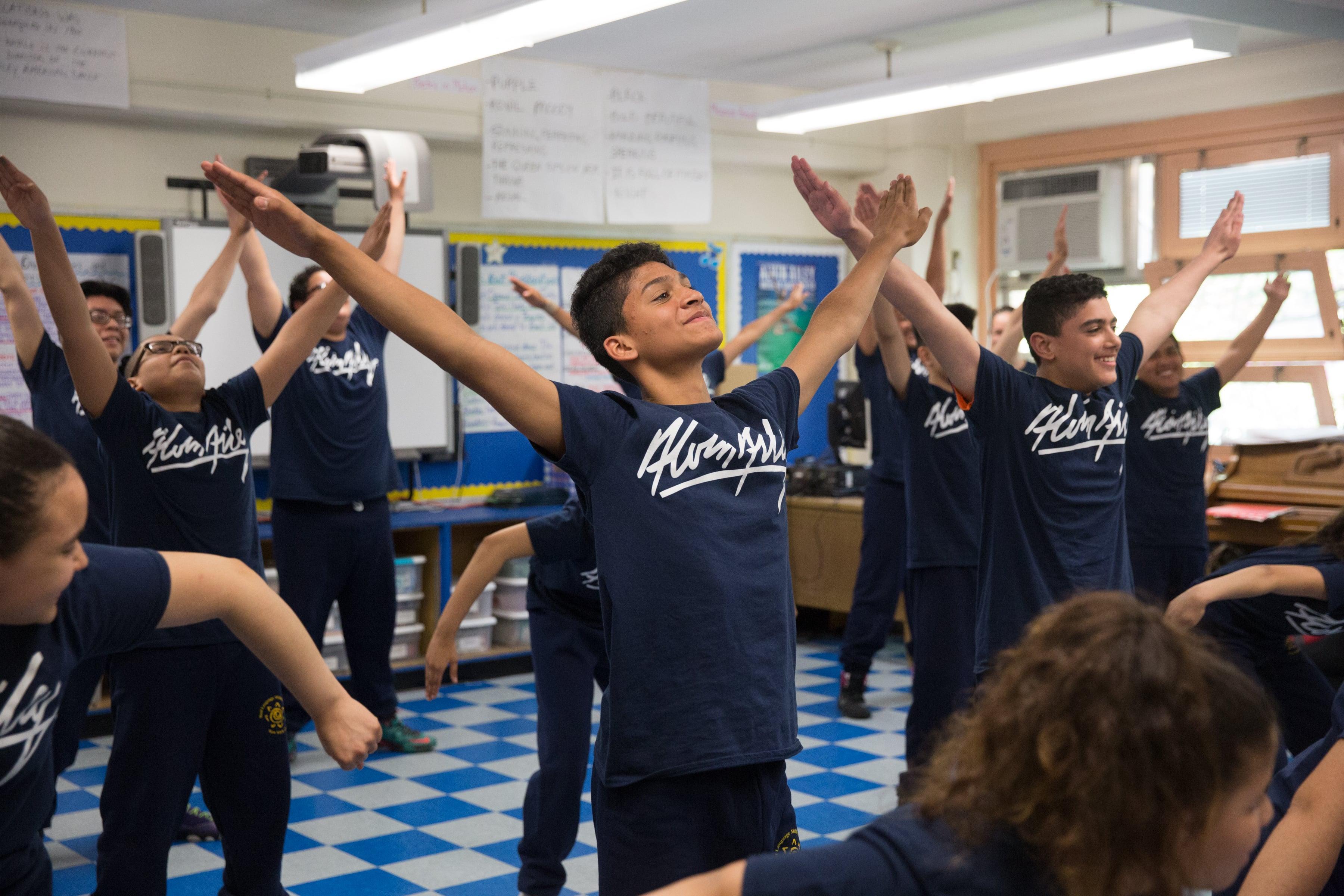 Ailey Dance Kids raising their arms wide apart