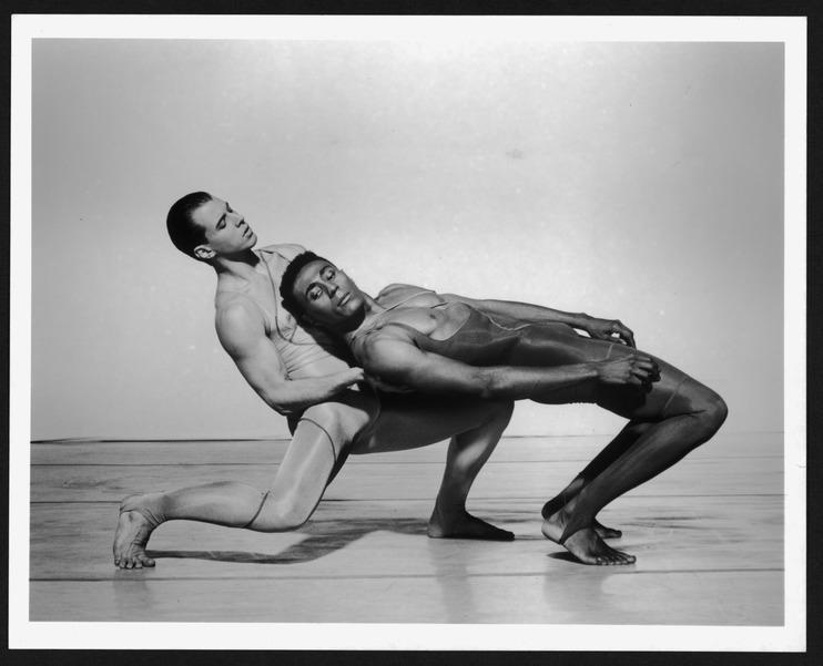 Black and white photo of Jonathan Riseling and Andre Tyson performing in Judith Jamison's "Forgotten Time." Riseling is supporting Tyson, who is leaning back dramatically. Both dancers are in fitted costumes, and the stage background is plain, focusing on their expressive movement. Photo by Jack Mitchell, 1990.