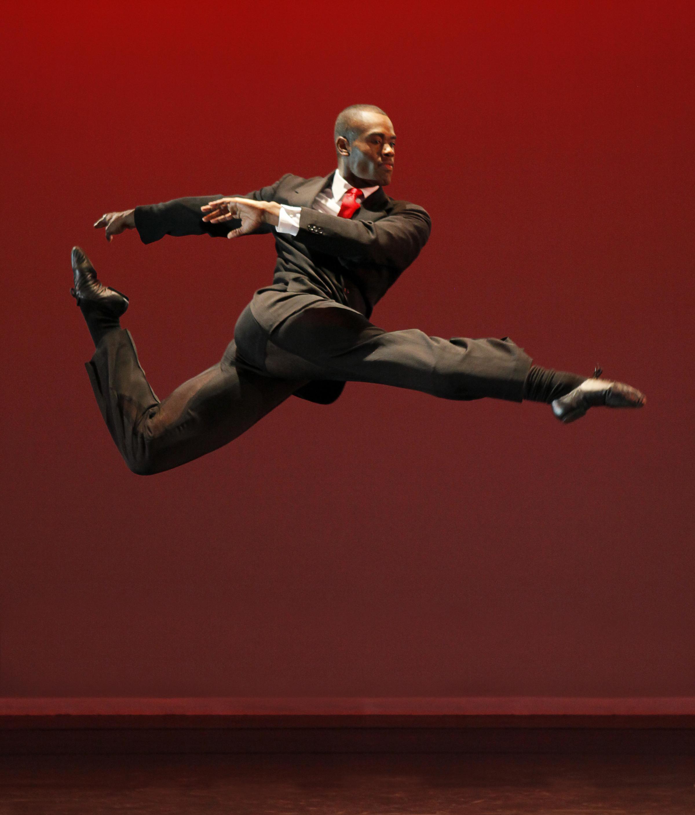 Bald dancer in a suit, leaping in the air