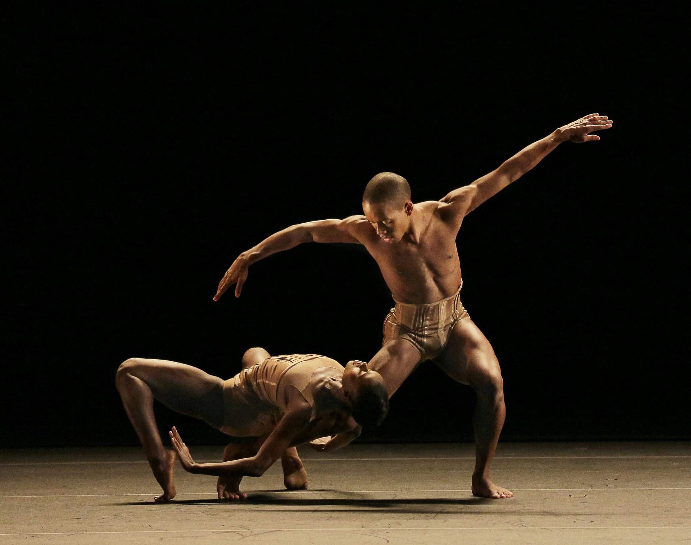 Photo of a dancer leaning on another's leg