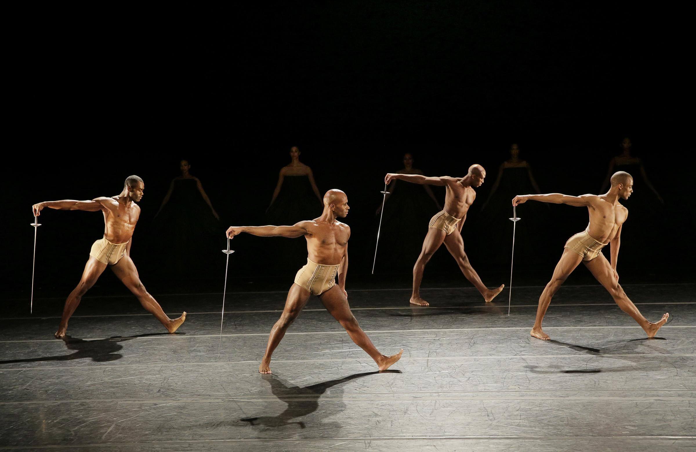 Photo of four Ailey dancers holding fencing swords downward in Petite Mort