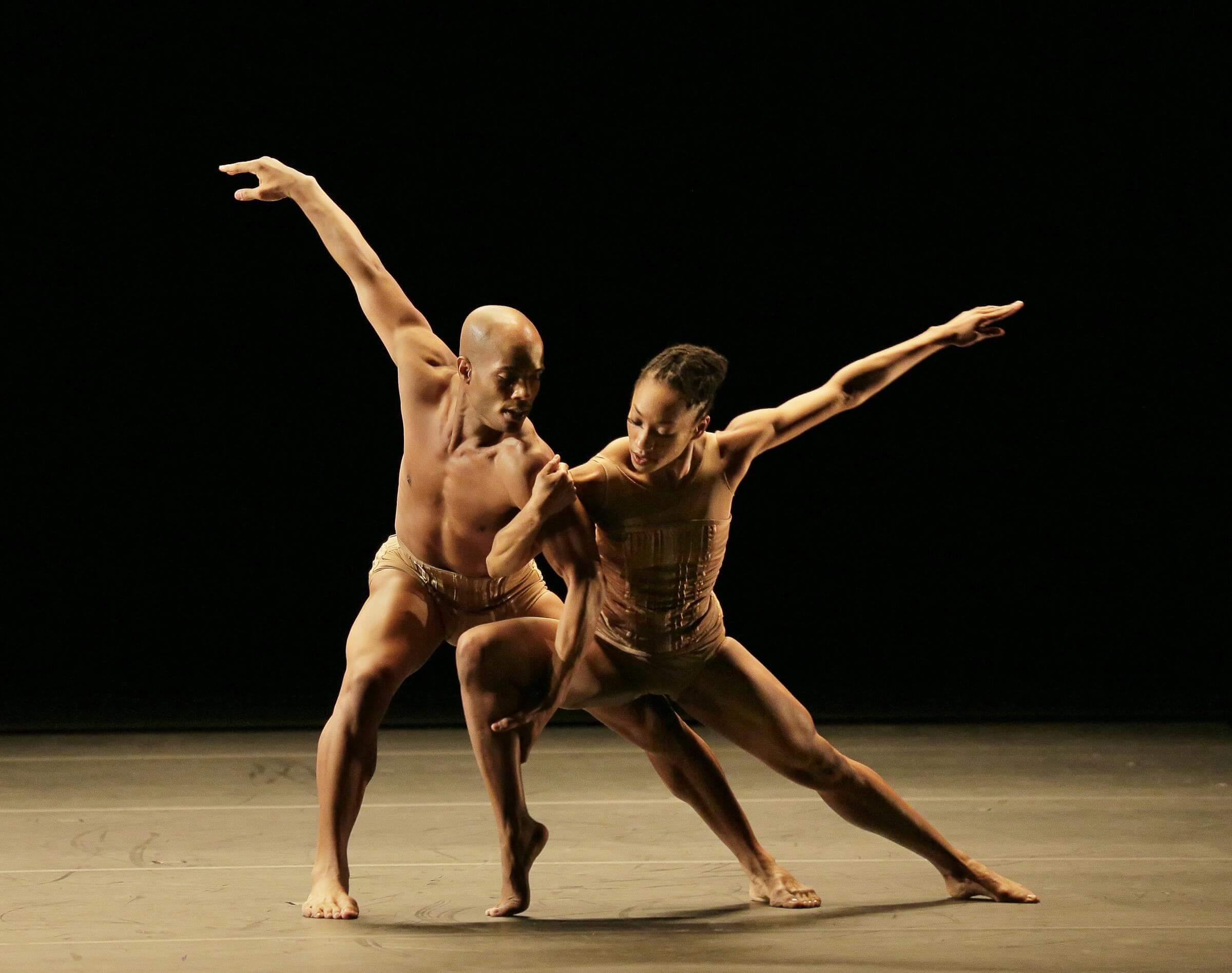 Photo of two dancers with their arms interlocked