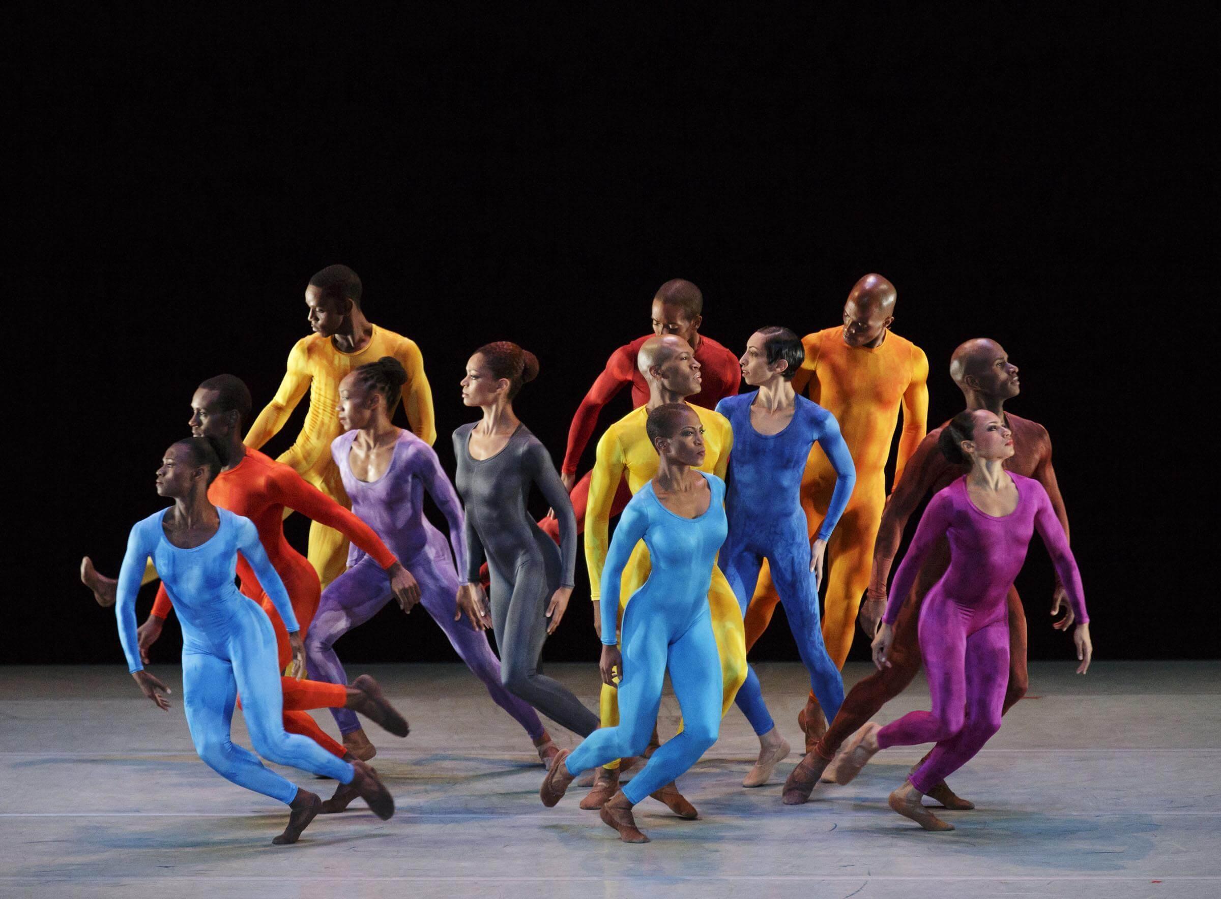 Photo of ailey dancers grouped together in colorful outfits