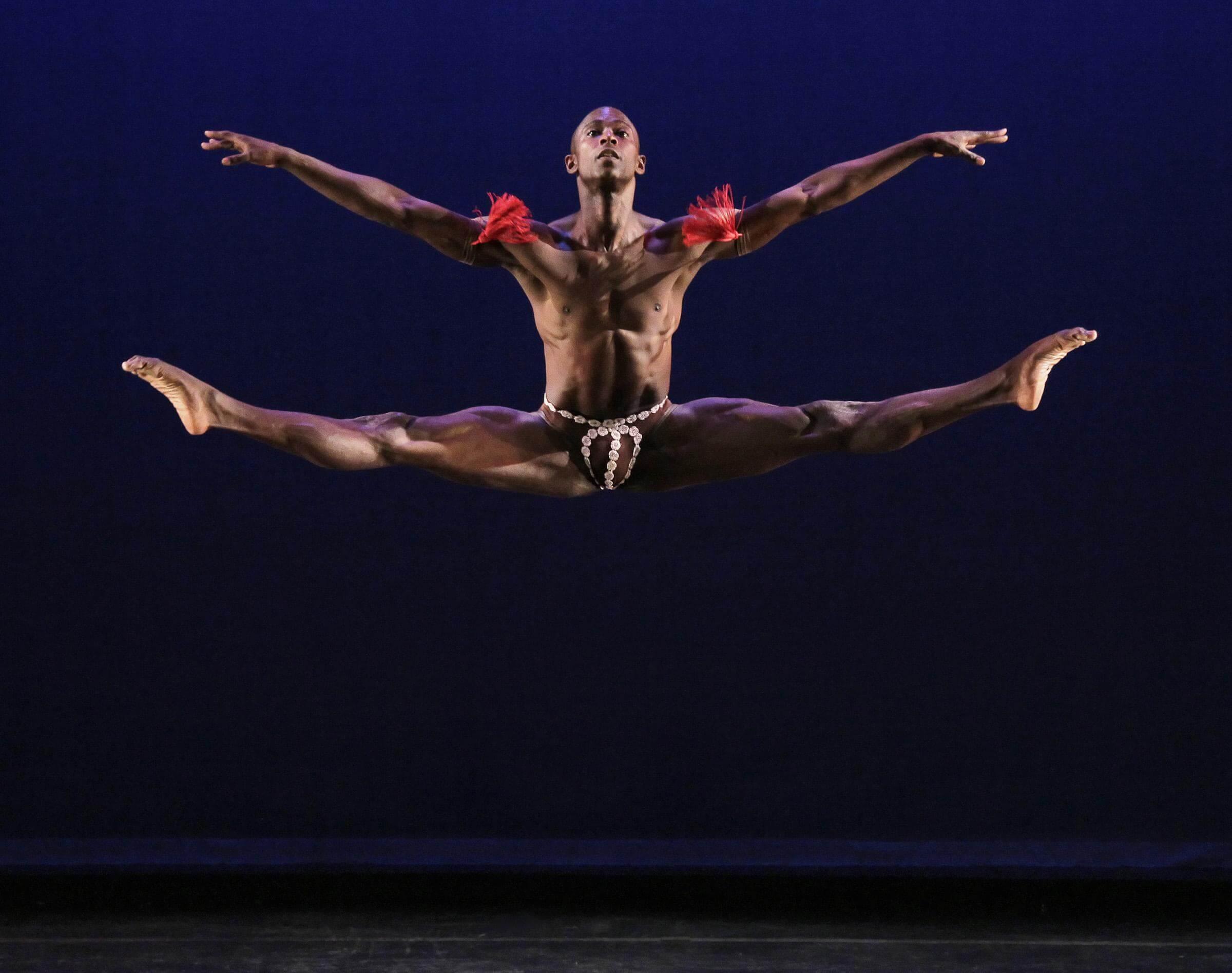 Photo of a dancer in the air with their arms and legs extended