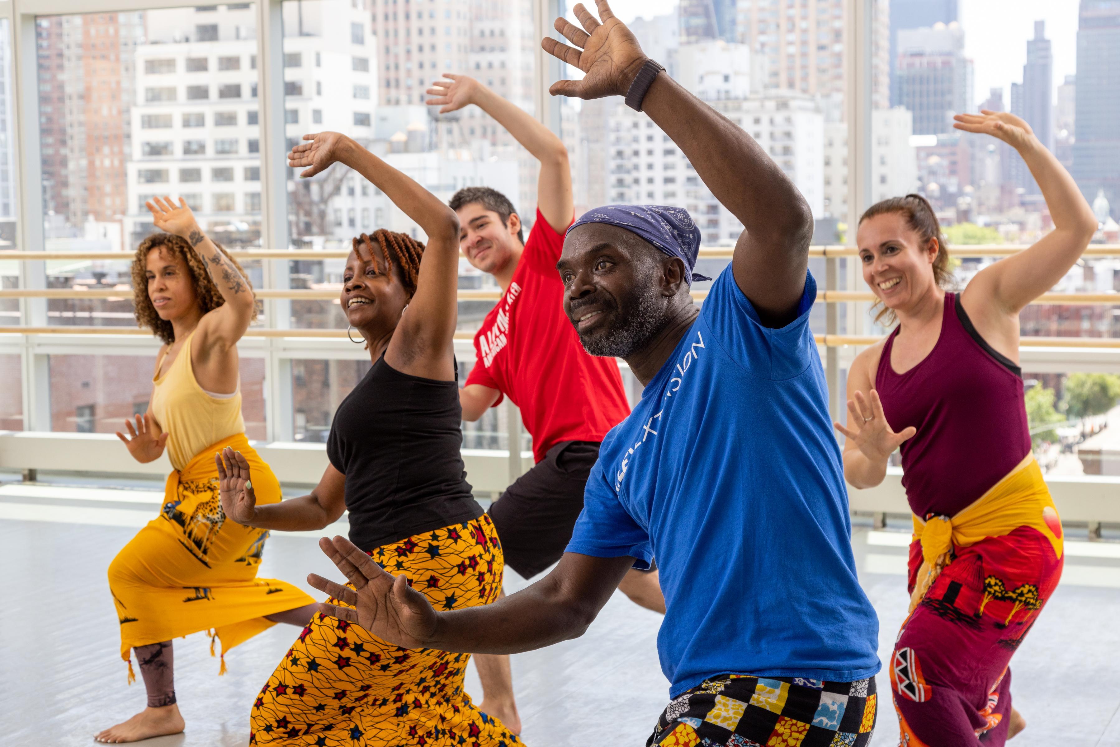 West African class including dancers of all backgrounds with their arms upward and palms outward