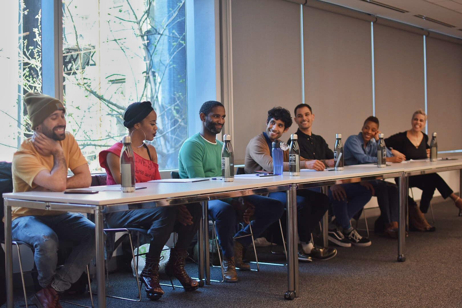 A panel of alumni sitting at a desk and smiling