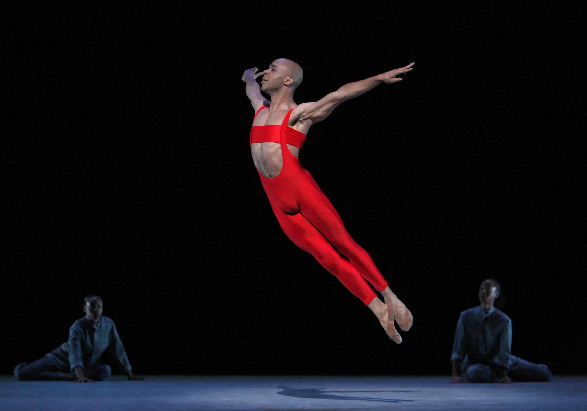 A dancer in red leaping in the air like a bird