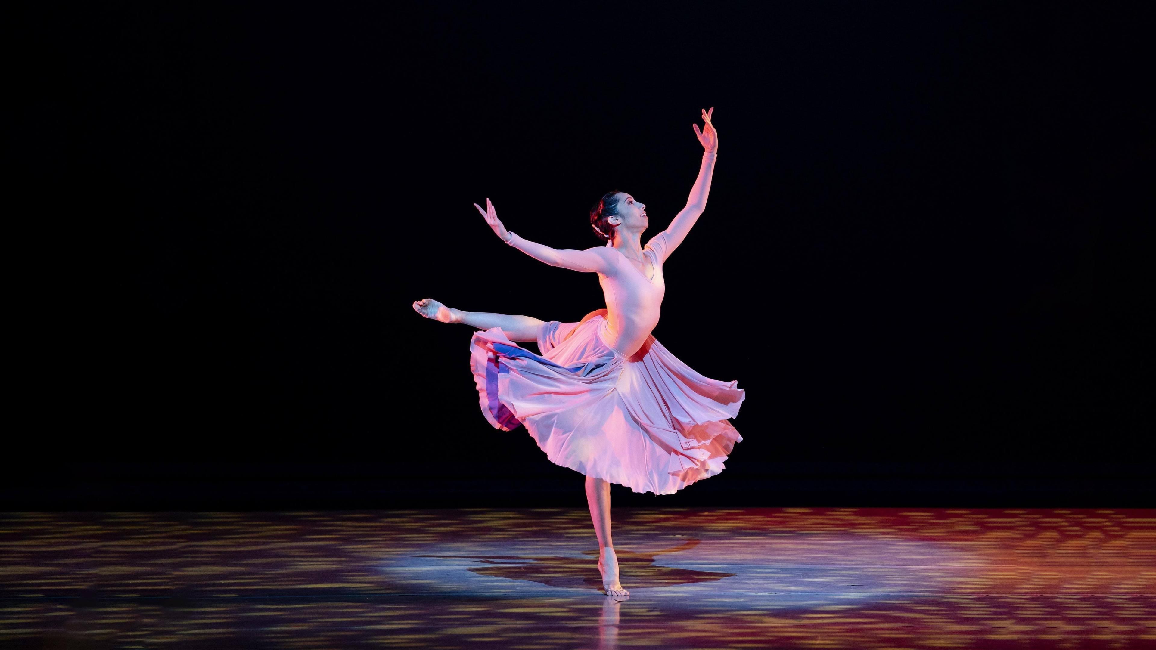 A dancer is on stage in a dress in arabesque