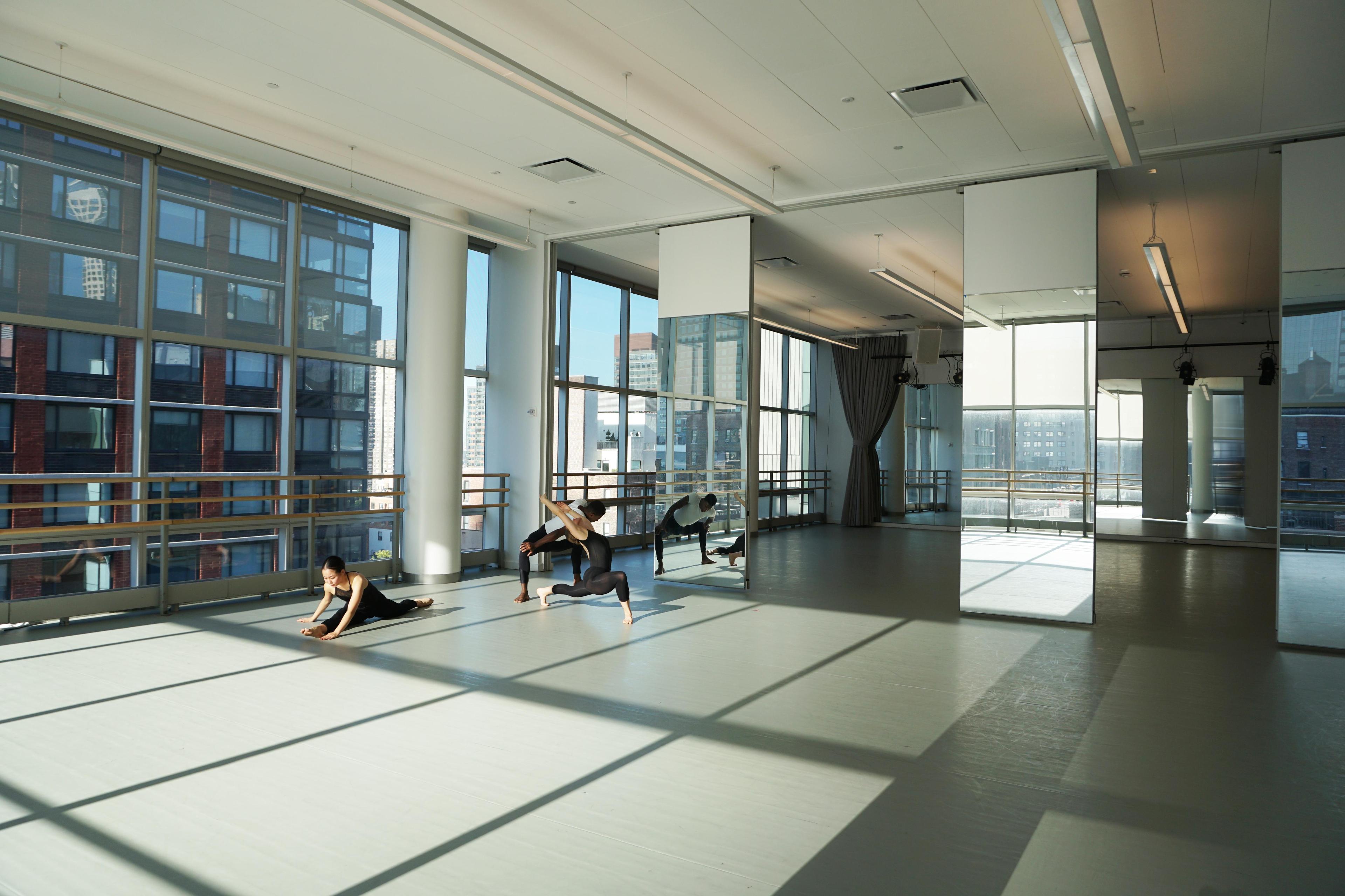 Dancers in an Ailey Studio stretching, with sun reflections on the floor