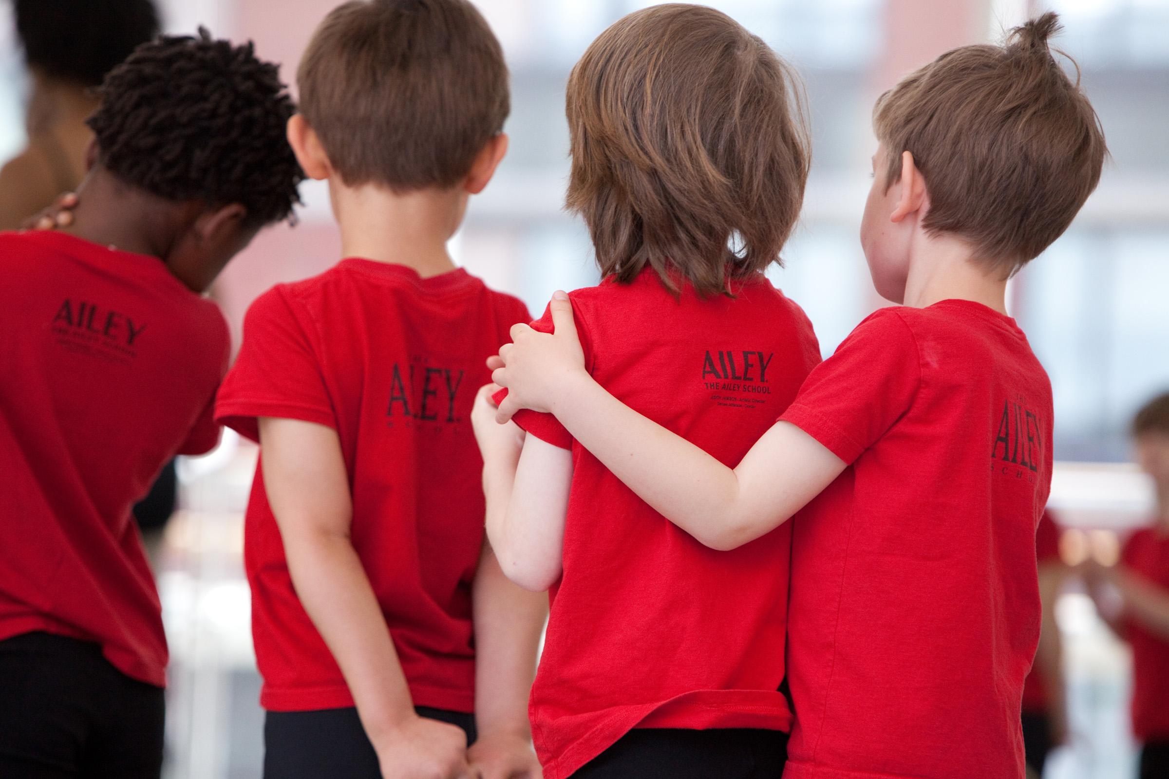 A group of boys in red tee shirts in a conga line