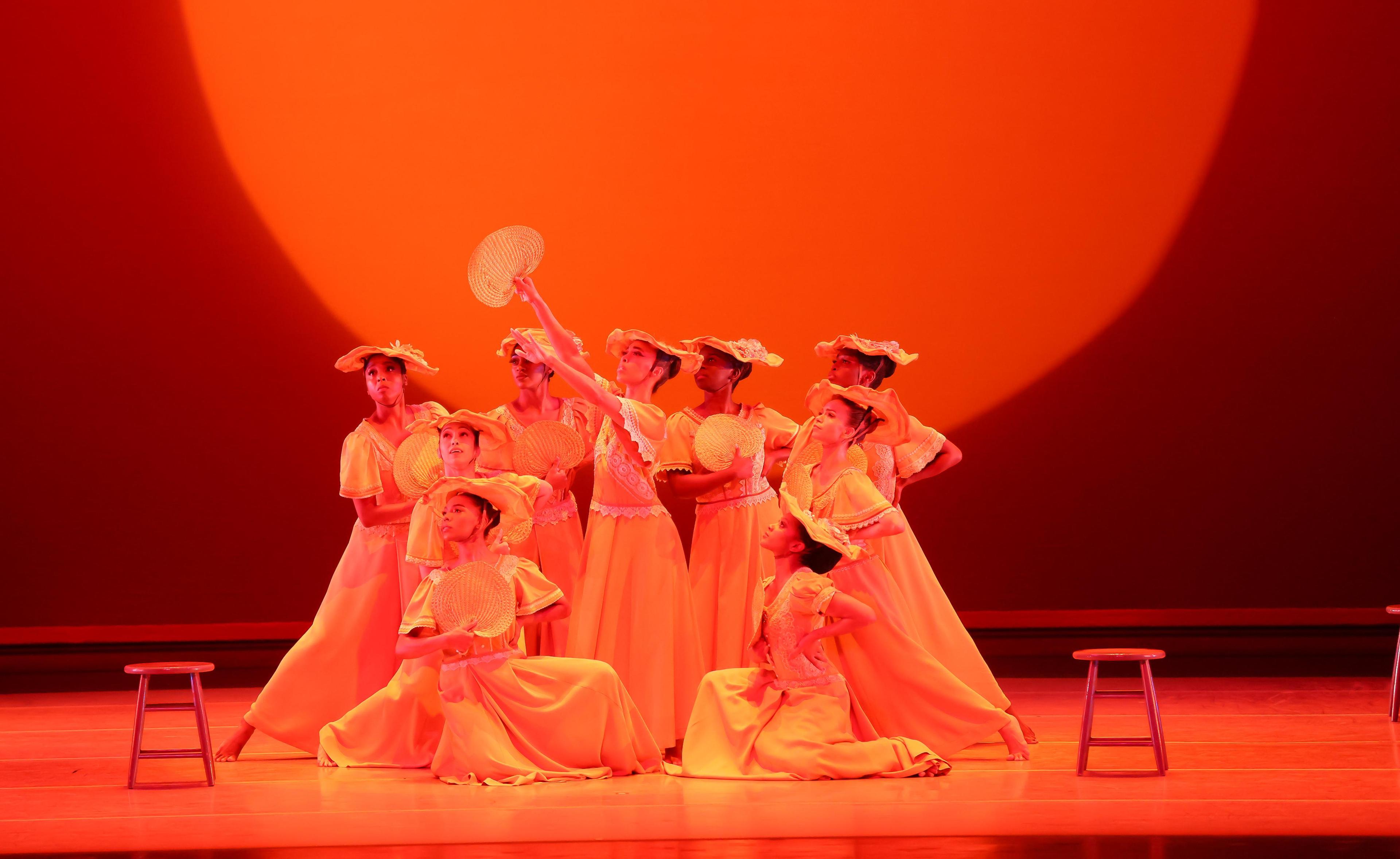 a group of women in yellow dresses and hats crowd together