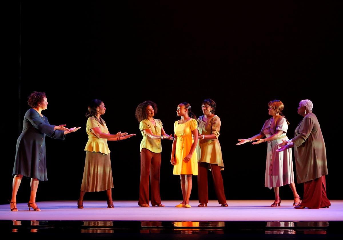 a group of people in a semi-circle arounda a girl in a yellow dress