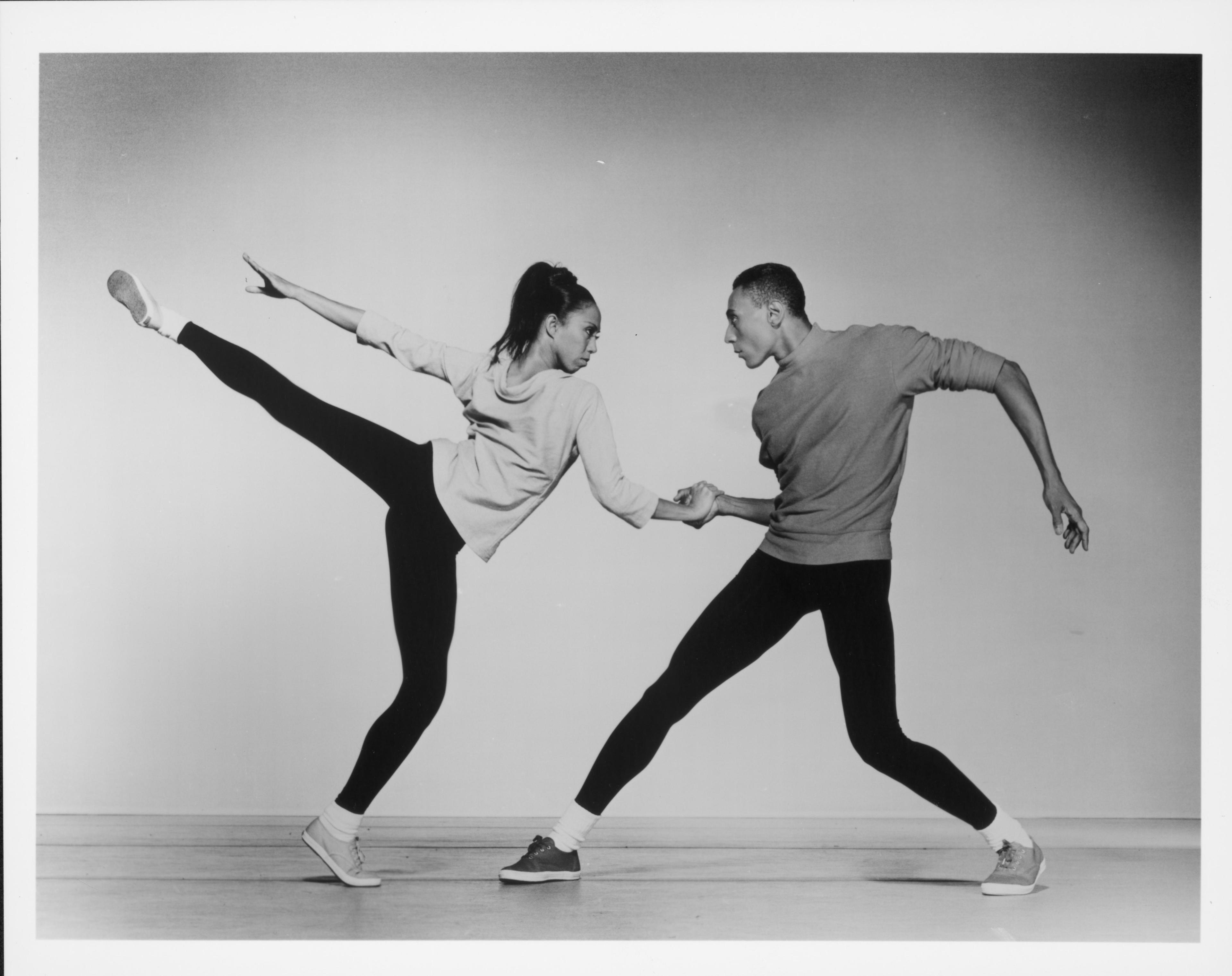 a female dancer kicking one leg behind her facing a male dancer who is looking back at her