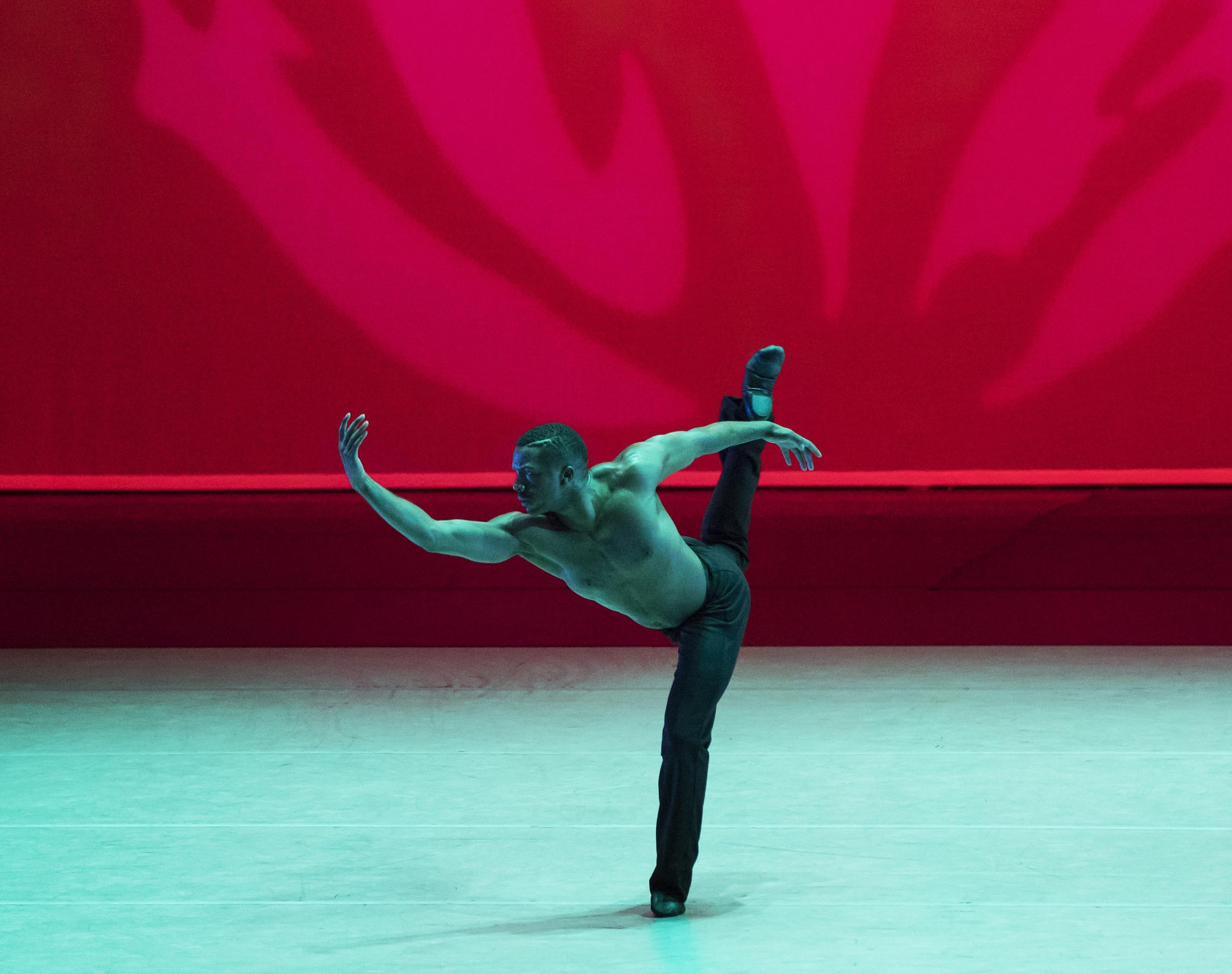 One dancer with black pants, one leg backward in attitude and one arm curved forward