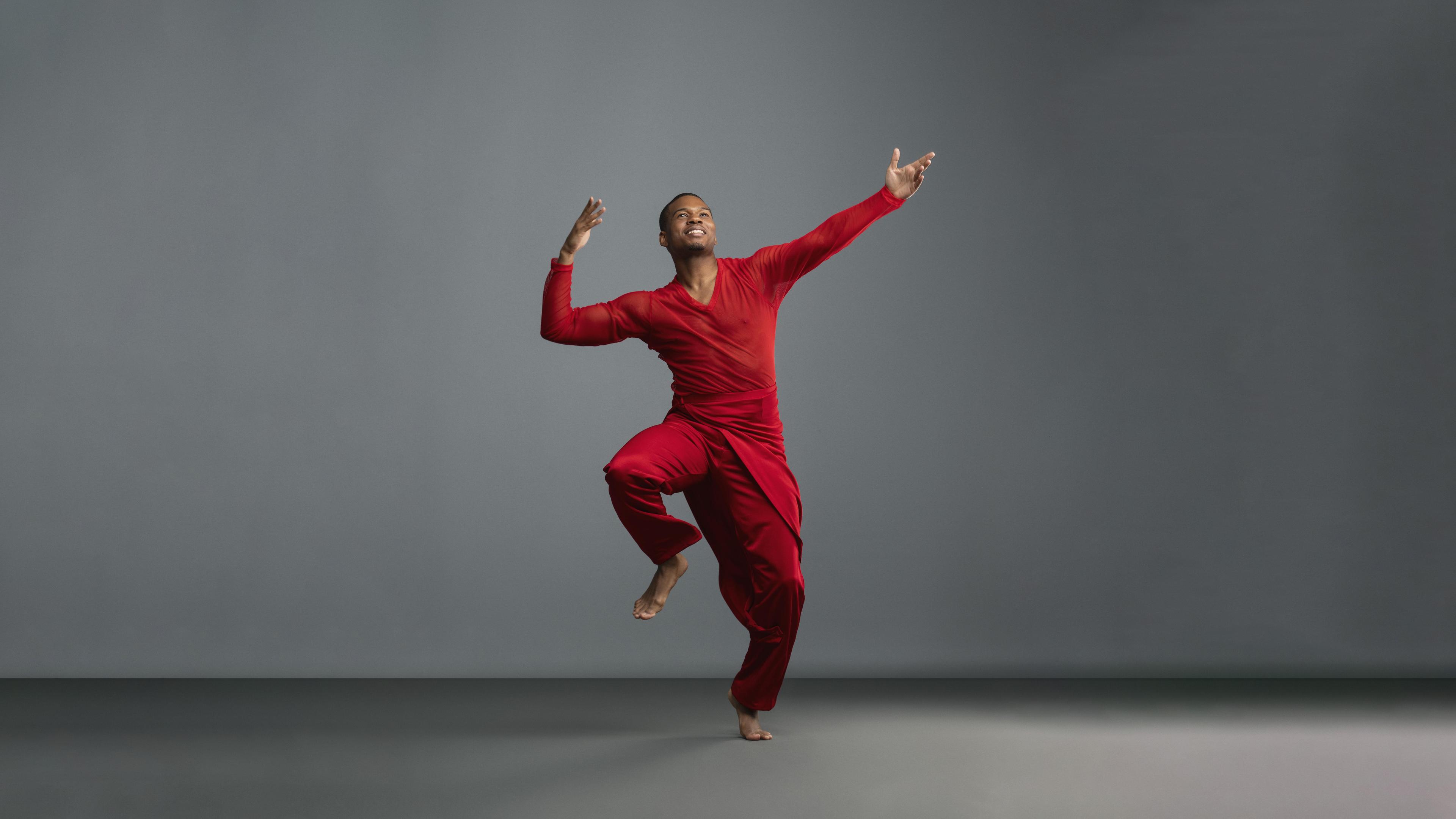 Dancer in red. He is dancing in a grey studio.