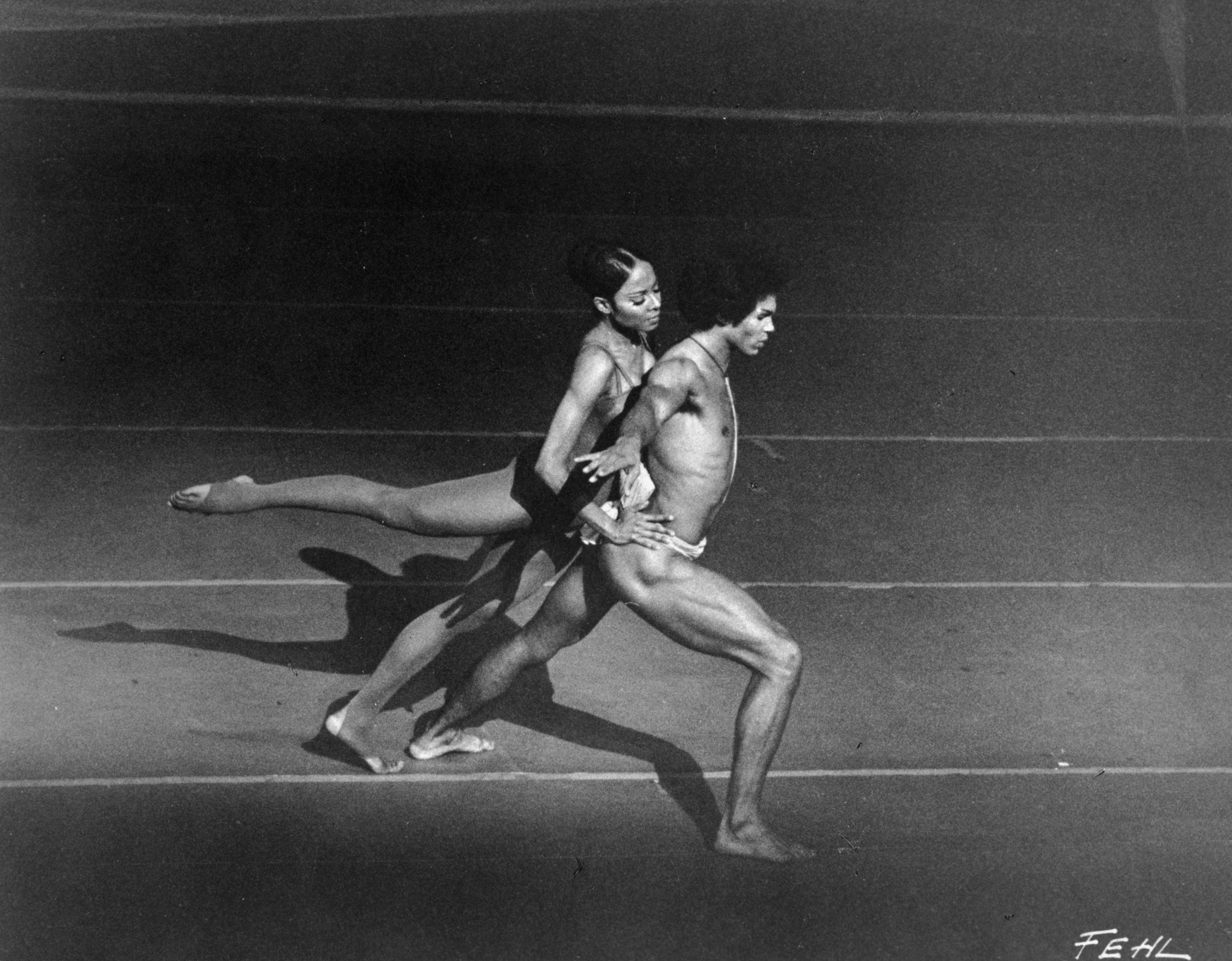 A man lunges forward as a woman leans forward on his back